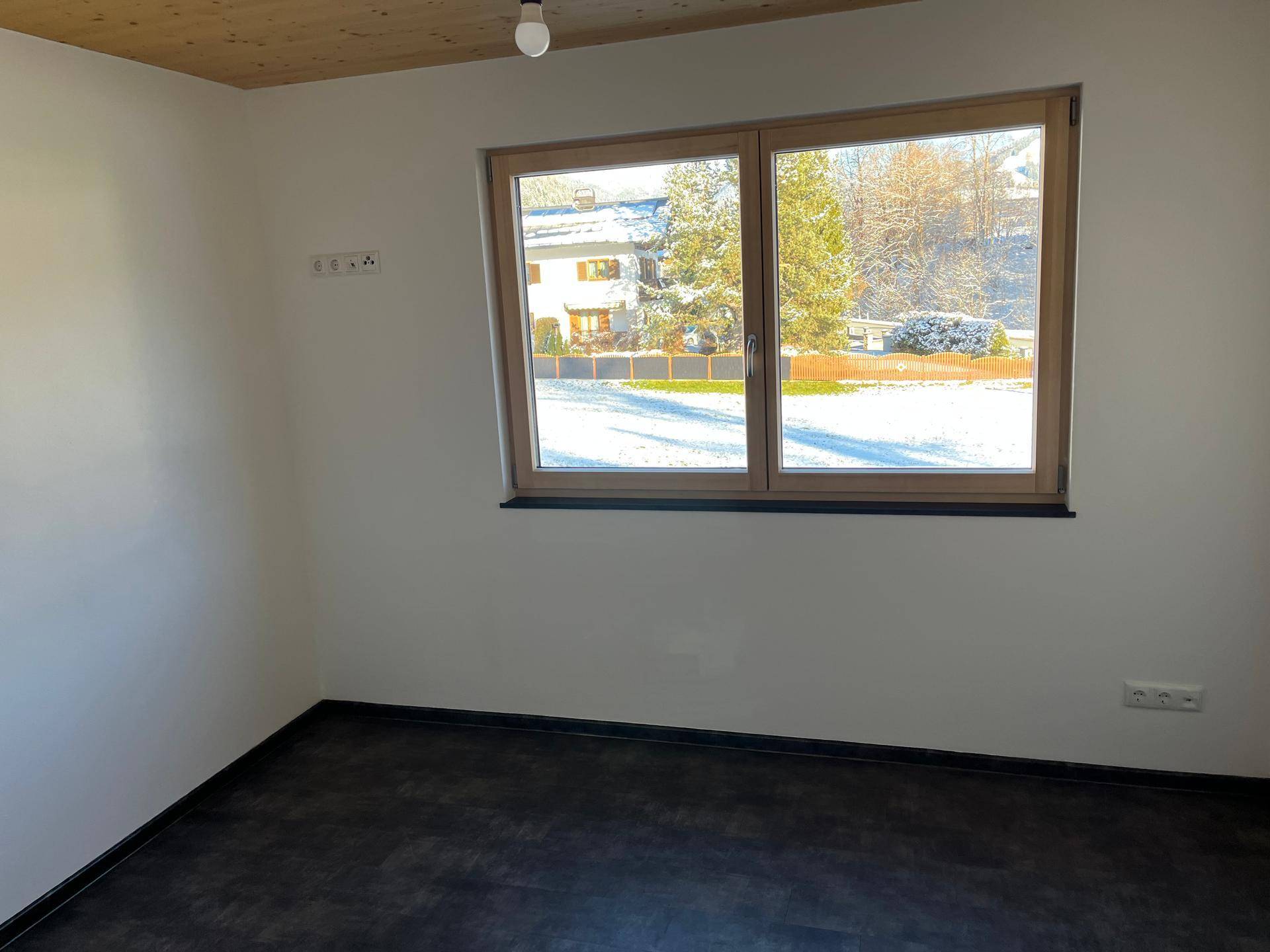 Geräumiges Schlafzimmer mit dunklem Boden, Holzdecke und Blick auf die Umgebung.