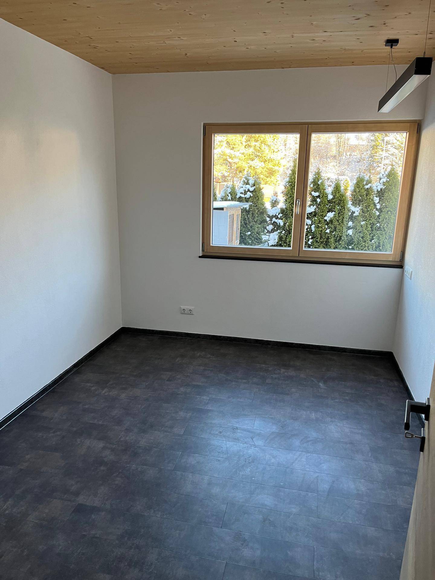 Helles Zimmer mit Holzboden und Blick ins Grüne, ideal als Schlaf- oder Kinderzimmer.