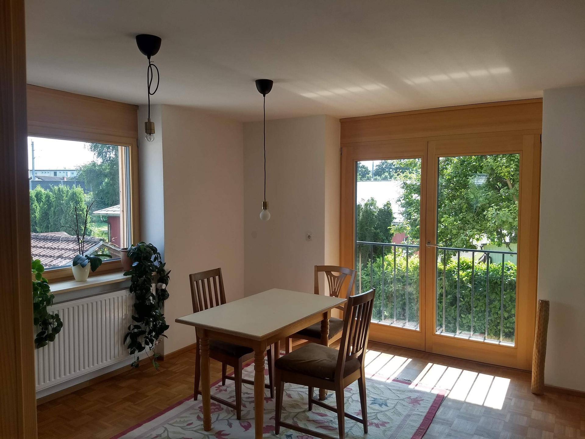Essbereich mit Holztisch und Stühlen, Parkettboden und Zugang zu einem Balkon.
