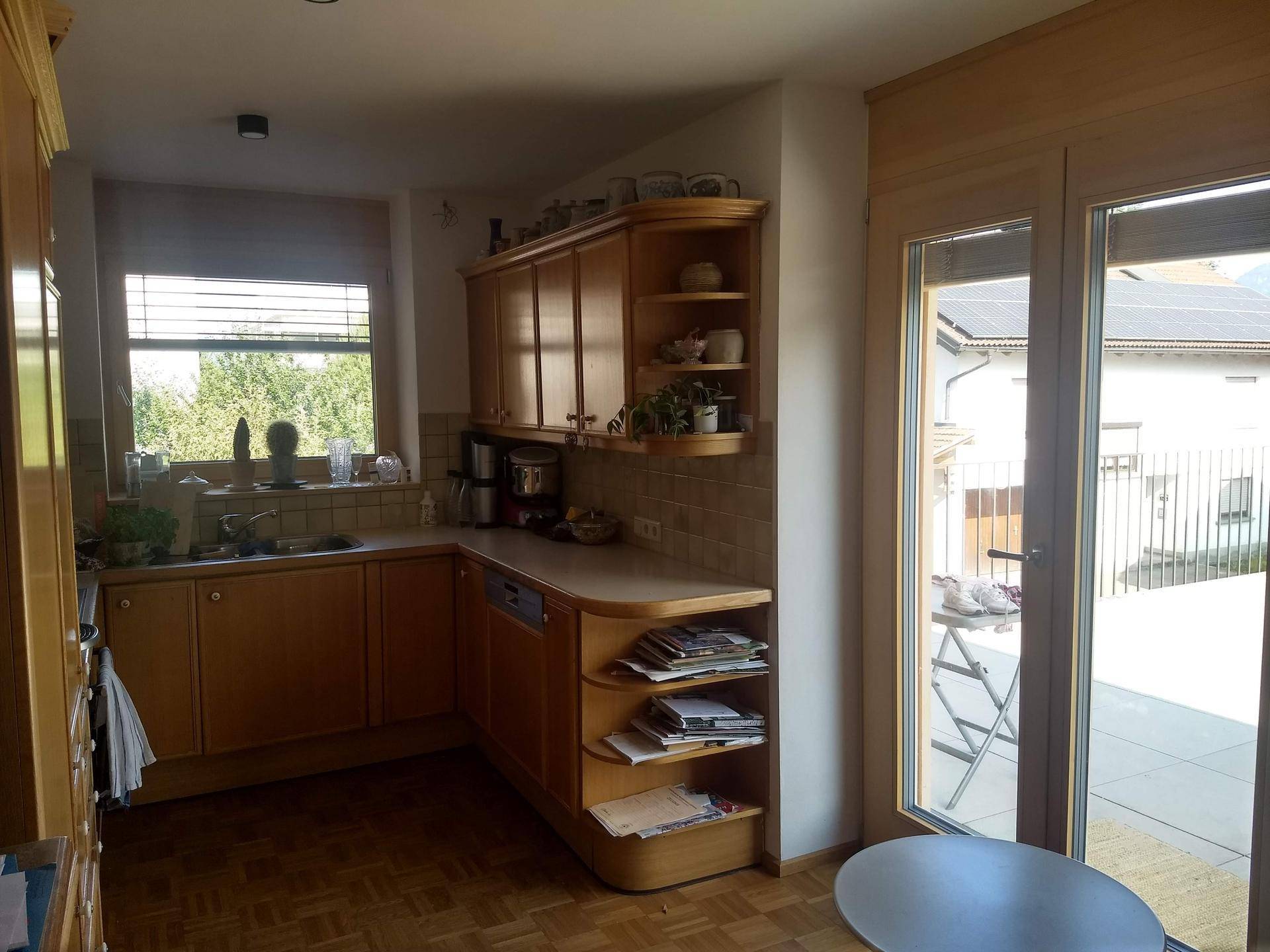Funktionale Küche mit Holzschränken, Einbaugeräten und direktem Zugang zur Terrasse.