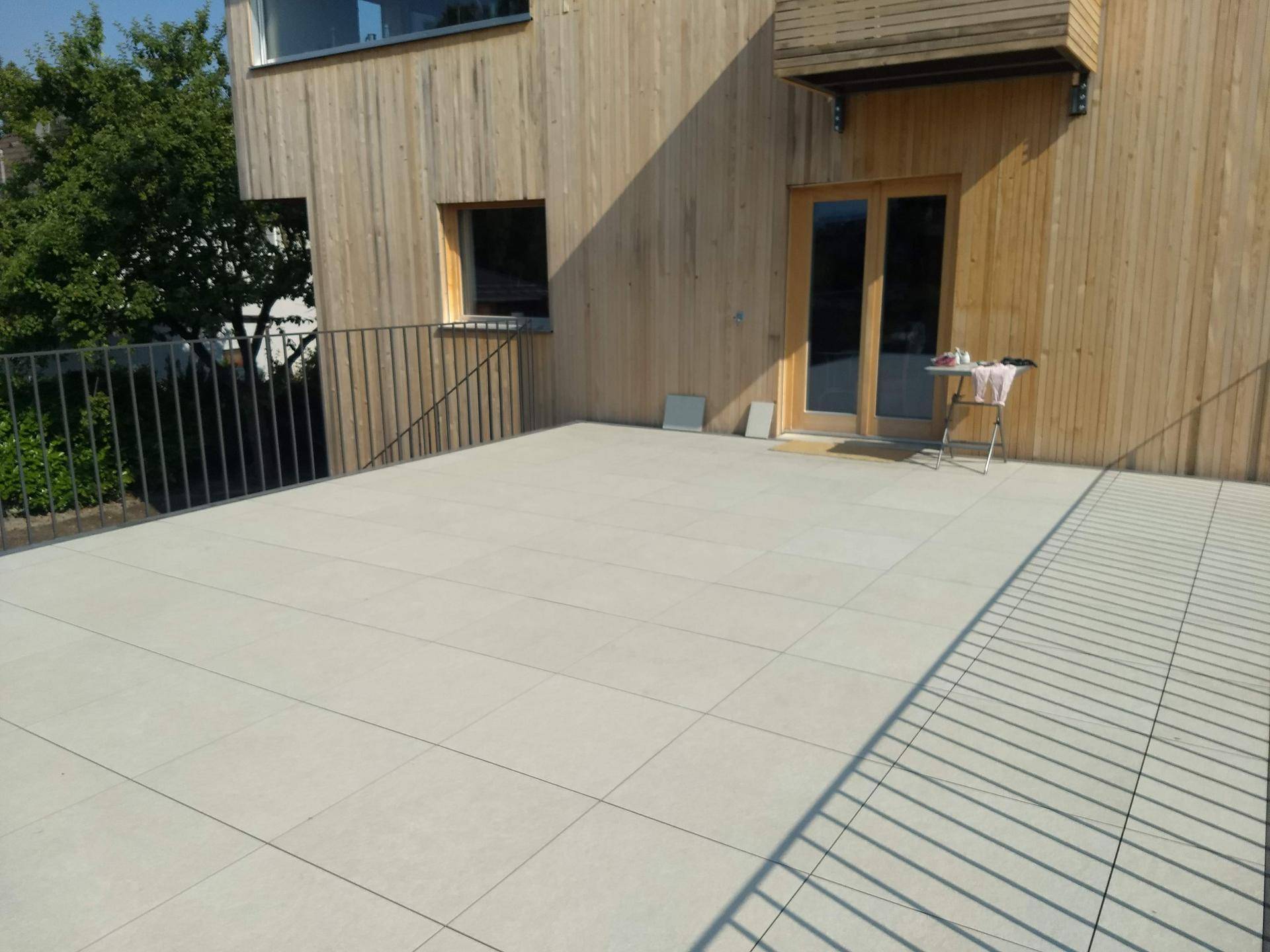 Geräumige, geflieste Terrasse mit Metallgeländer und Blick auf die Umgebung.
