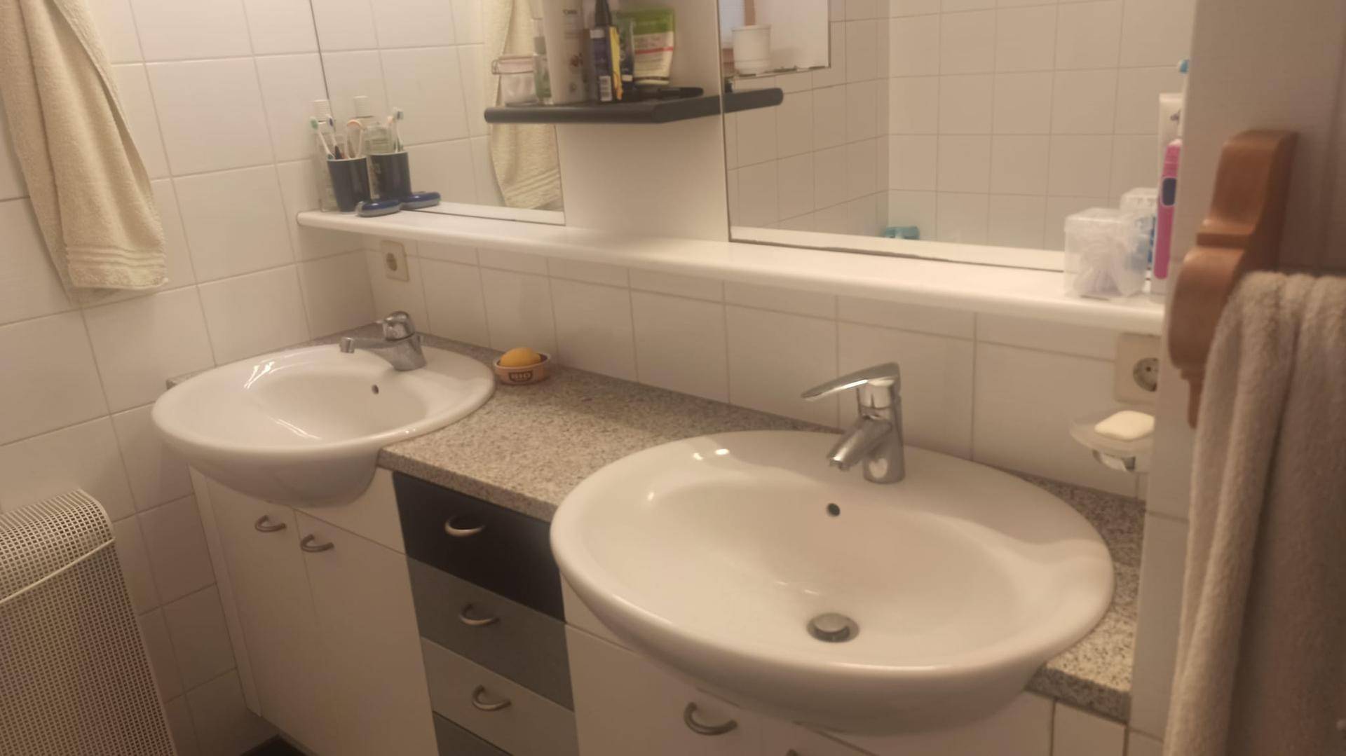 Badezimmer mit zwei Waschbecken, großem Spiegel und hellen Fliesen.