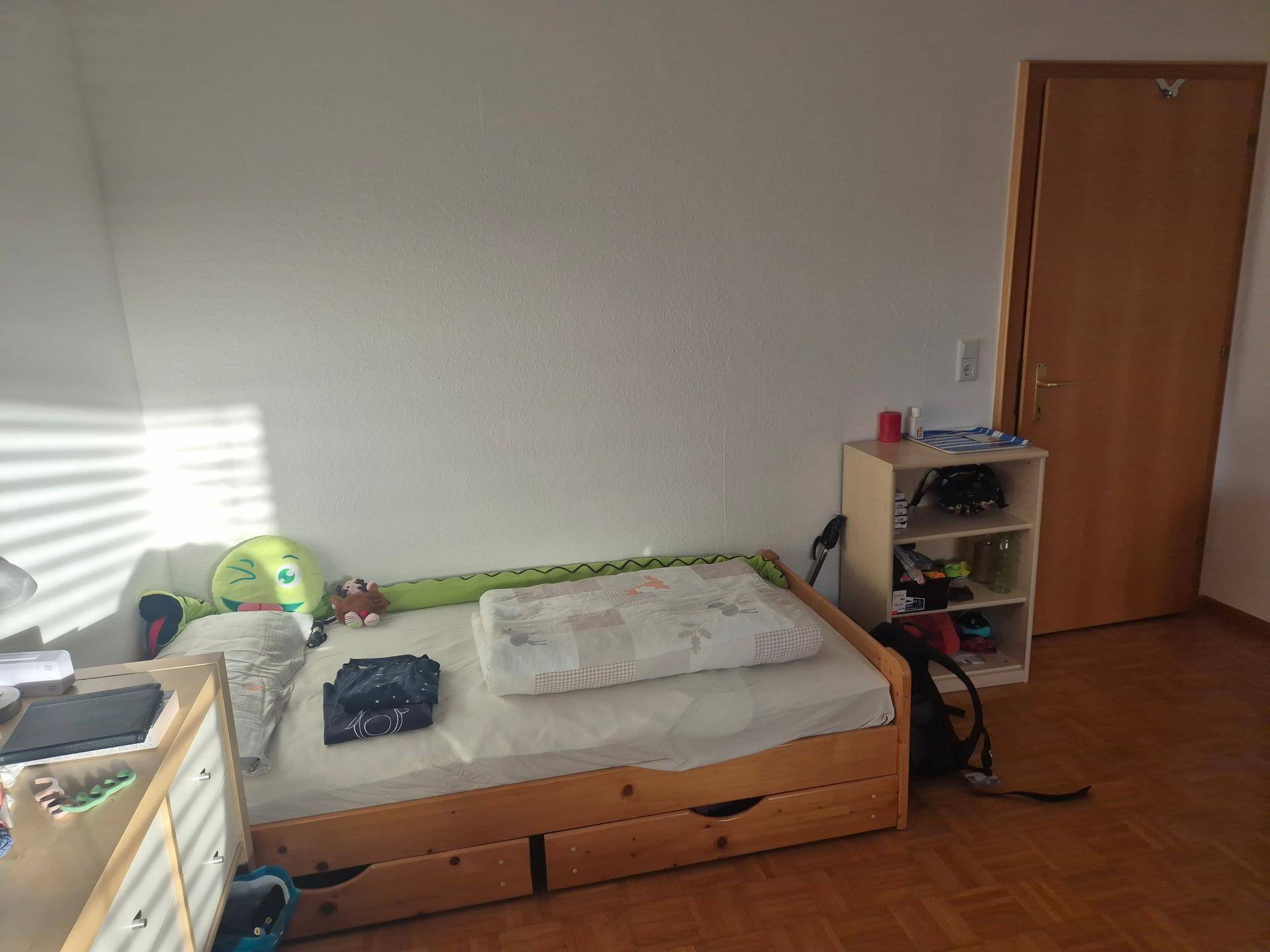Gemütliches Schlafzimmer mit Holzbett, integrierten Schubladen und Parkettboden.