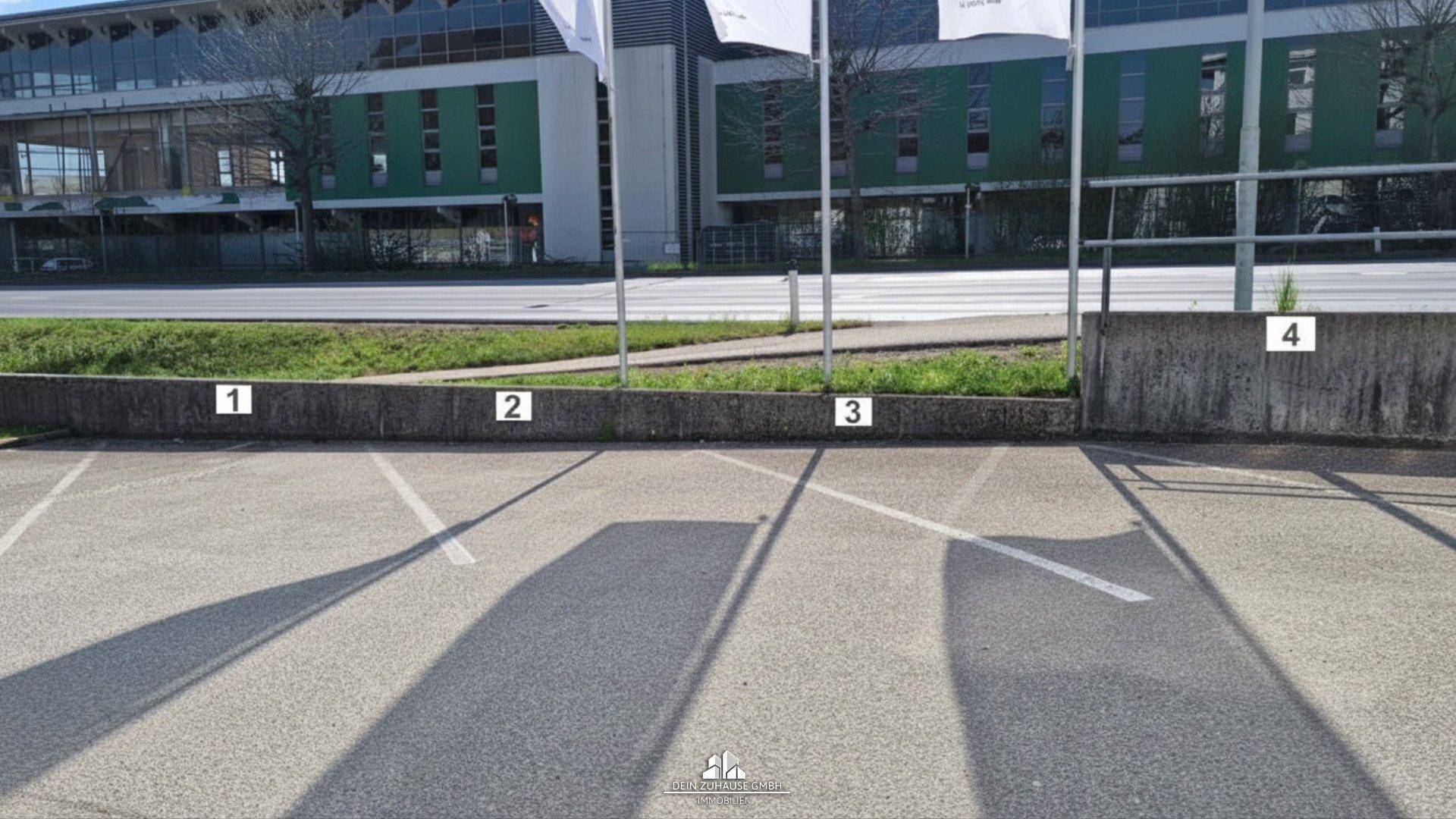 Außenparkplätze mit Markierungen und einer niedrigen Betonmauer im Vordergrund.