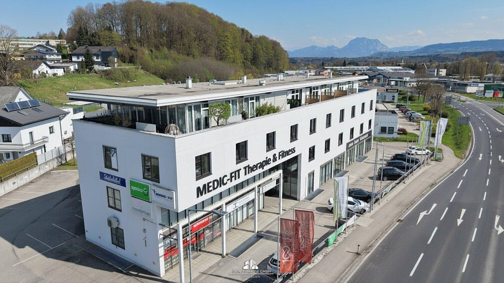 Luftaufnahme eines modernen Geschäftsgebäudes mit Flachdach und umliegenden Parkplätzen.