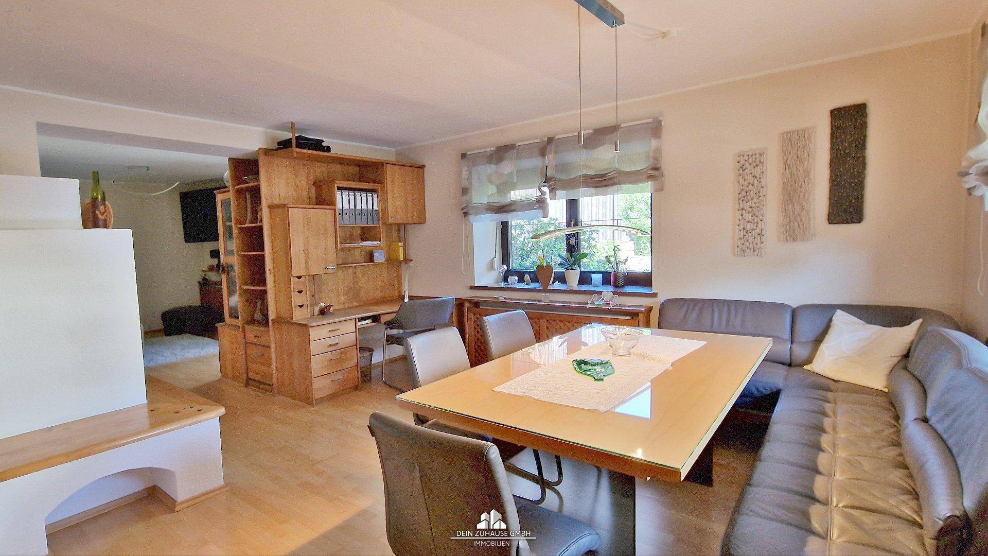 Gemütlicher Wohn- und Essbereich mit Holzboden, großem Esstisch und Sofa.
