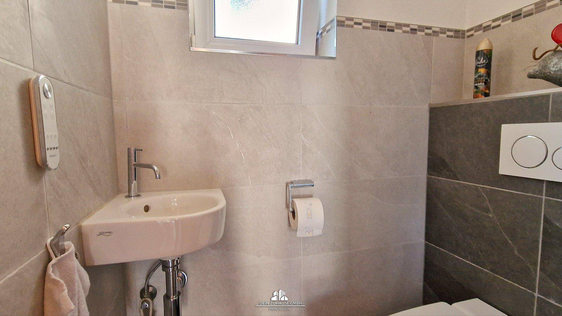 Modernes Gäste-WC mit kleinem Waschbecken, Wand-WC und Fenster.