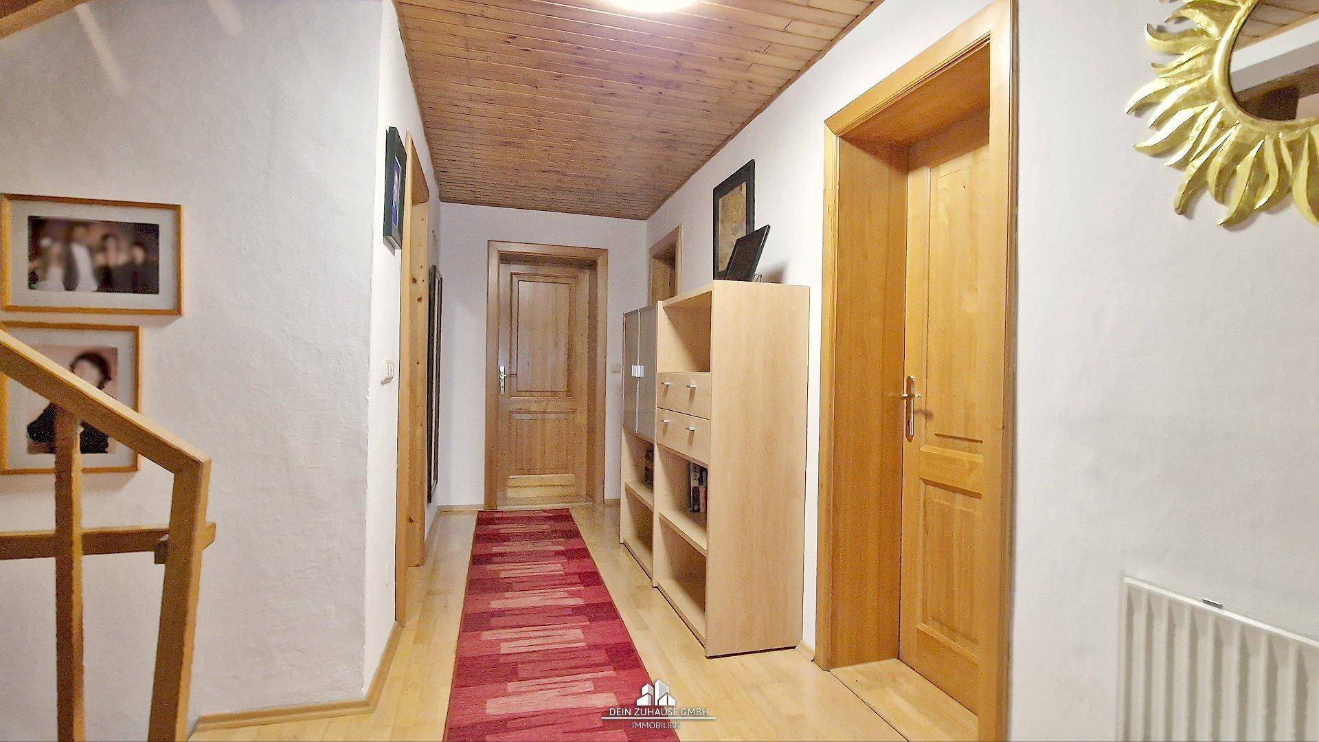 Heller Flur im Obergeschoss mit Holzdecke, Holzboden und Zugang zu weiteren Räumen.