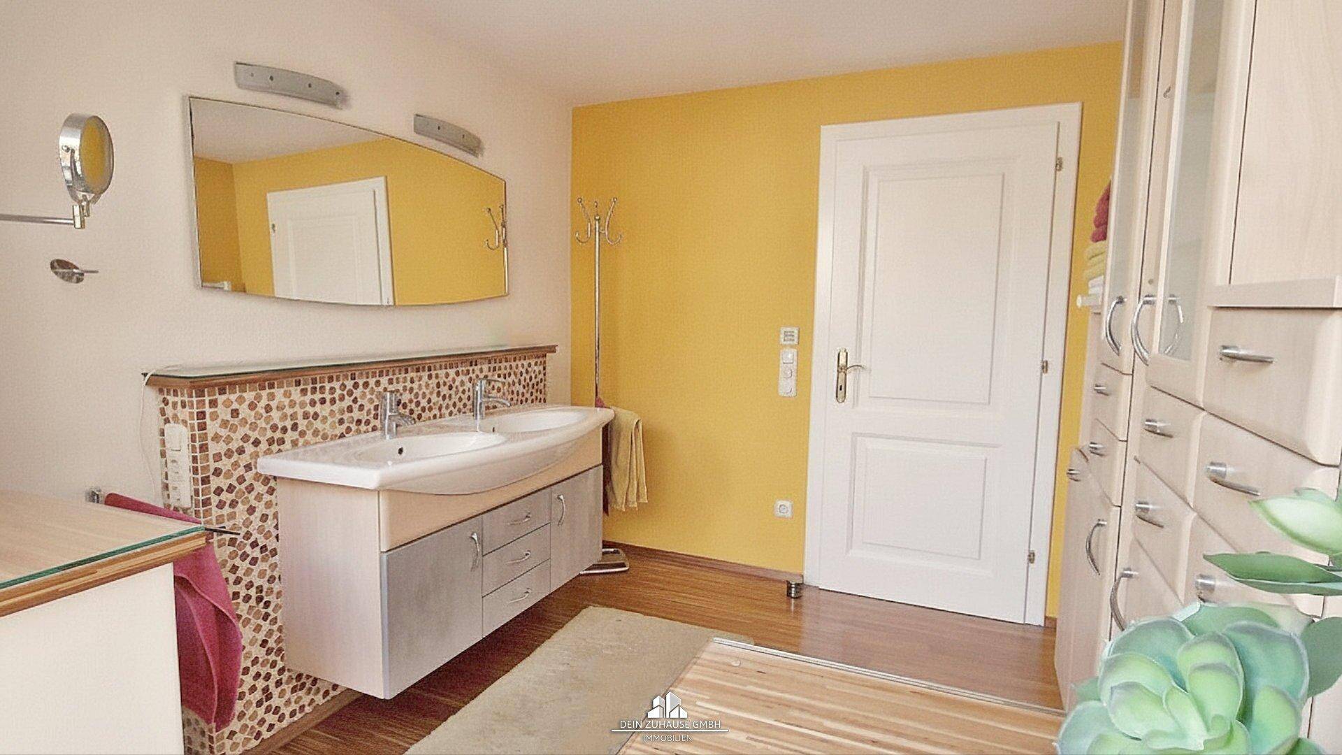 Badezimmer mit Doppelwaschbecken, großem Spiegel und gelben Wänden.
