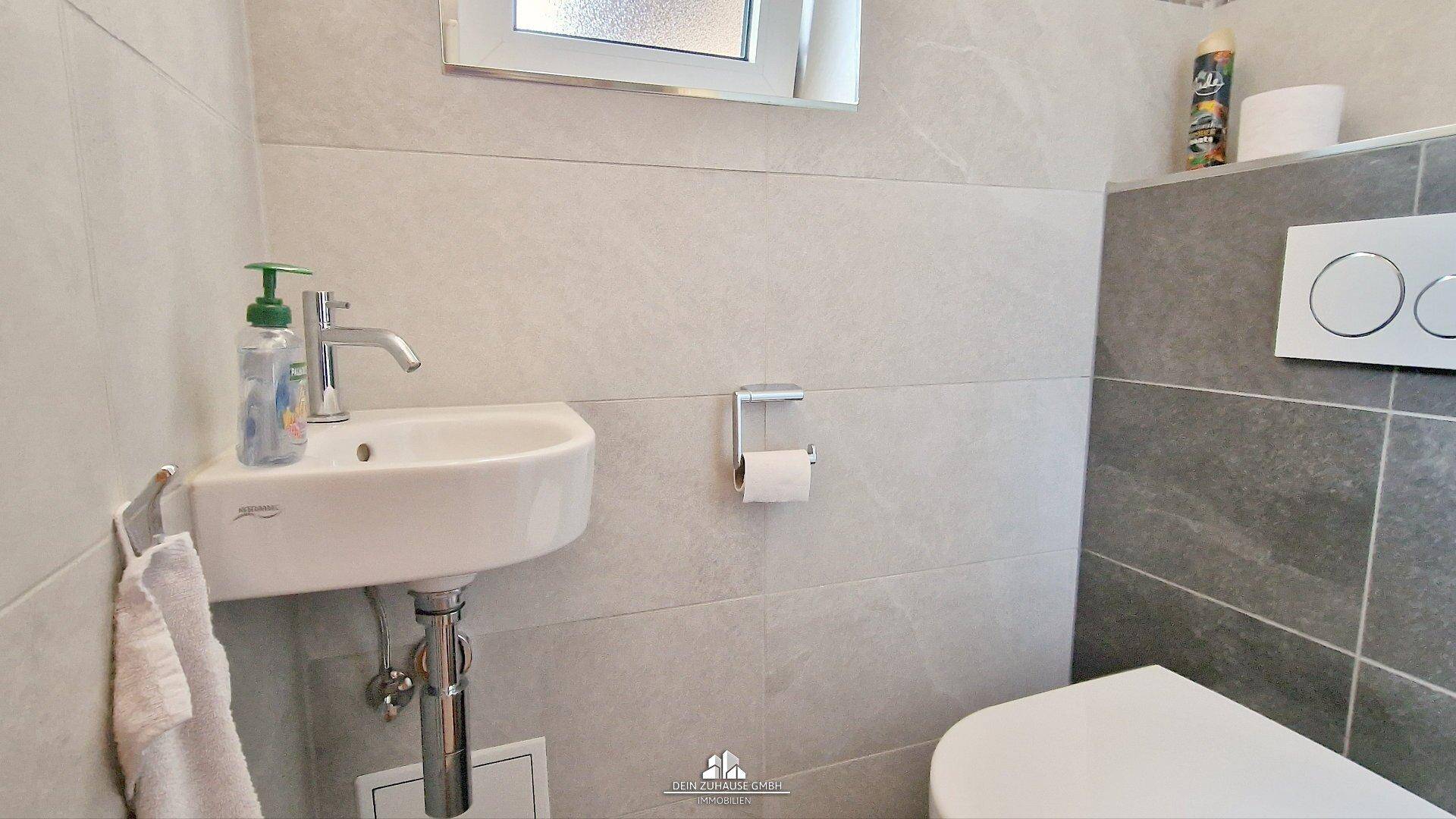 Modernes Gäste-WC mit kleinem Waschbecken, Wand-WC und Fenster.