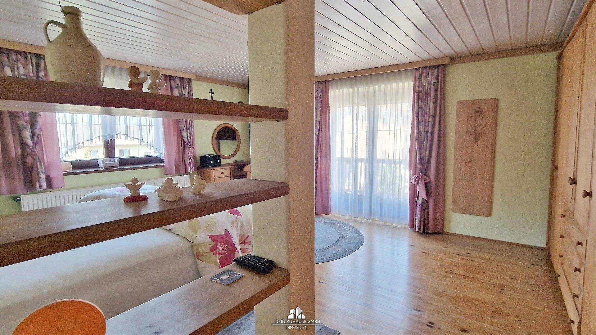 Gemütliches Schlafzimmer mit Holzboden, Holzdecke und Zugang zum Balkon.