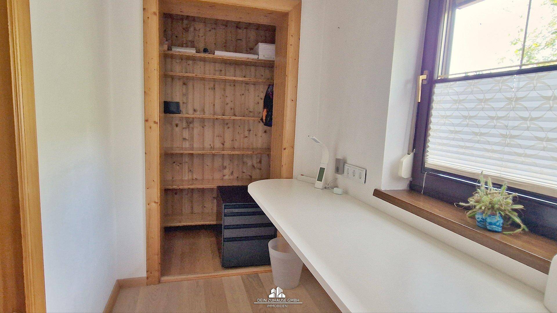 Kleines Arbeitszimmer mit Schreibtisch, Fenster und integriertem Regal.