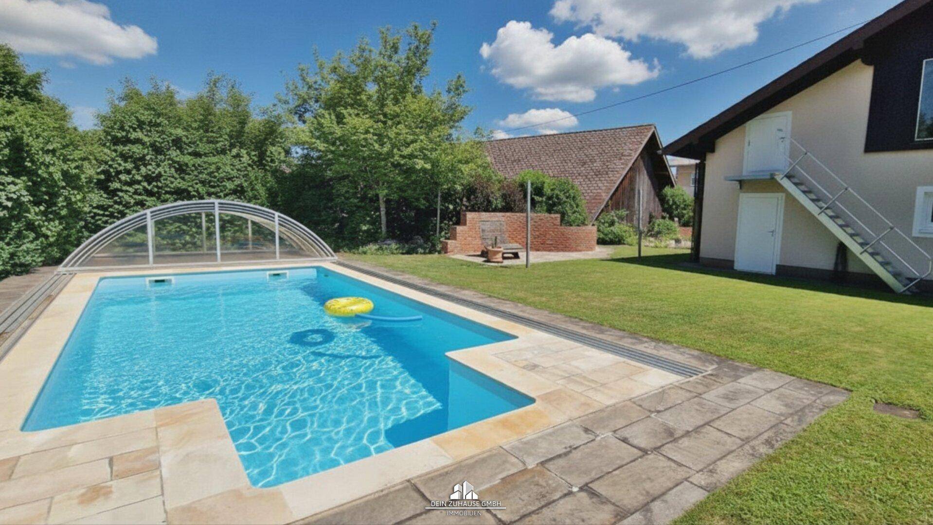 Großer Gartenbereich mit Swimmingpool und Überdachung, umgeben von Rasenfläche.