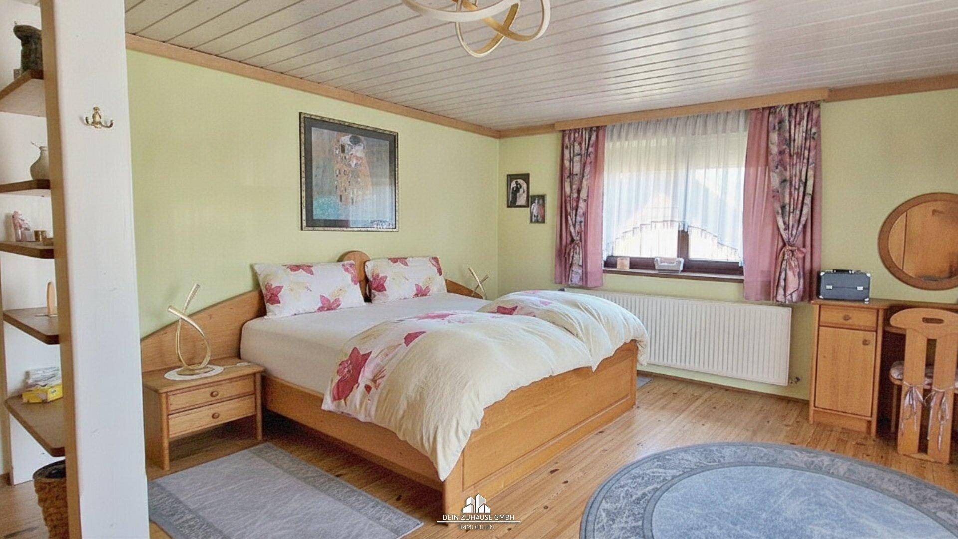 Schlafzimmer mit Doppelbett, Holzboden, Holzdecke und farbenfroher Dekoration.