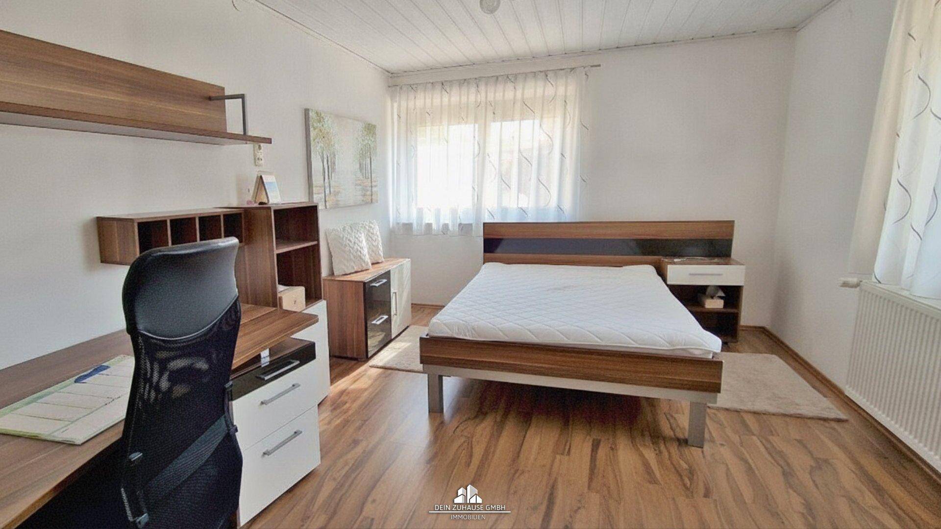 Helles Schlafzimmer mit modernem Bett, Schreibtisch und Holzboden.