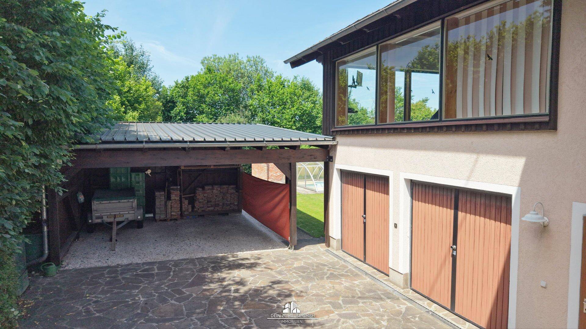 Außenansicht des Hauses mit großem Carport und zwei Garagentoren.