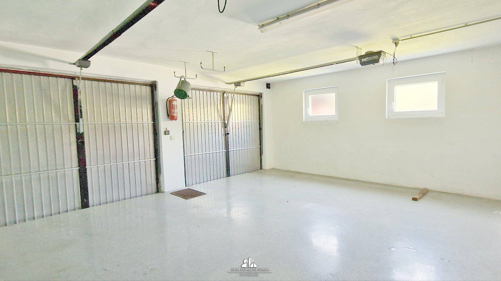 Geräumige Garage mit zwei Toren und Fenstern, bietet Platz für mehrere Fahrzeuge.