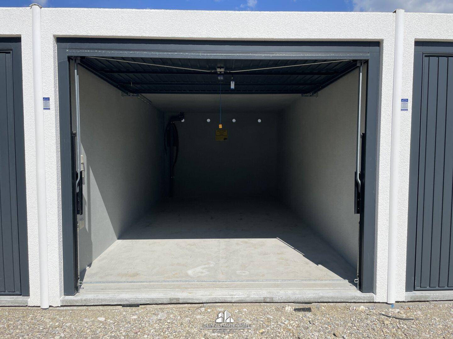 Leere Garagenbox mit offenem Tor und Betonboden.