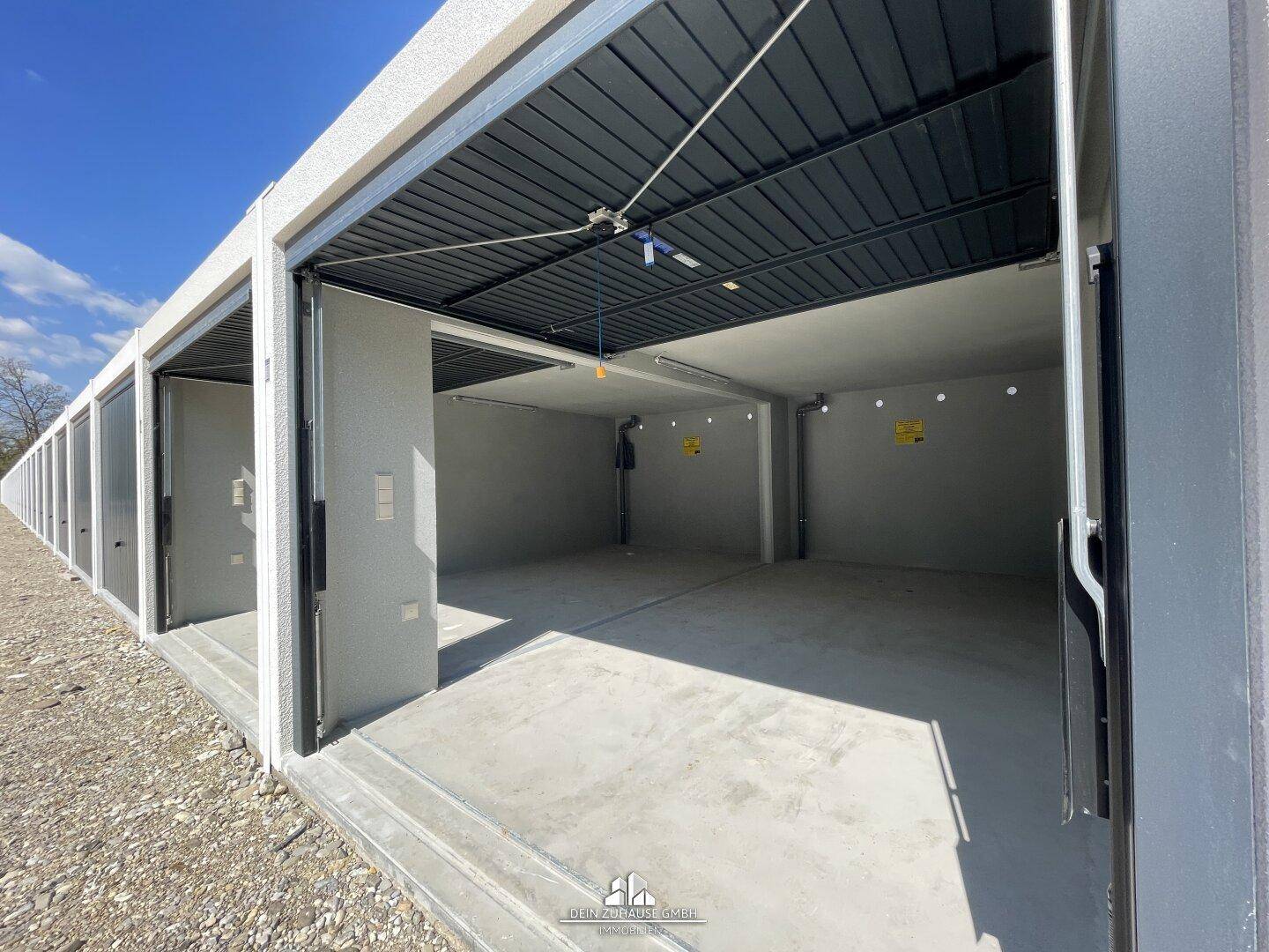 Blick in eine Reihe von offenen Garagenboxen mit Betonböden.