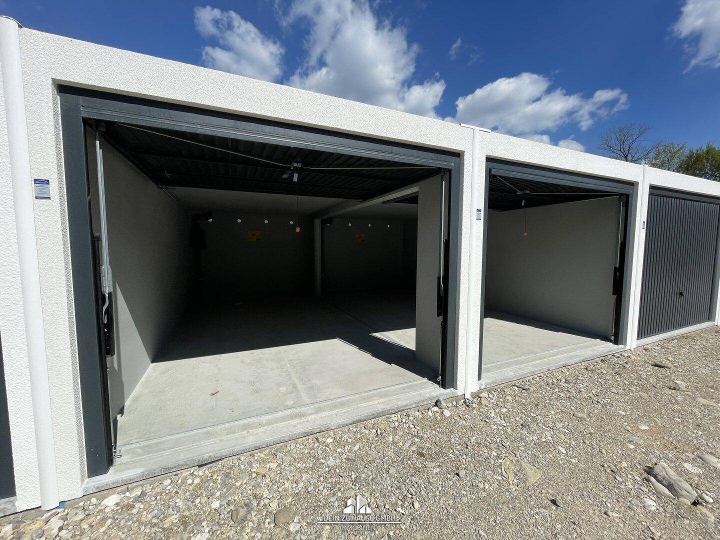 Mehrere offene Garagenboxen in einer Reihe unter blauem Himmel.