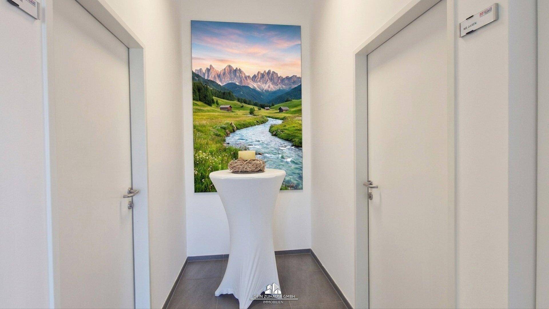 Heller Flur mit zwei Türen, einem Stehtisch und einem großen Landschaftsbild an der Wand.