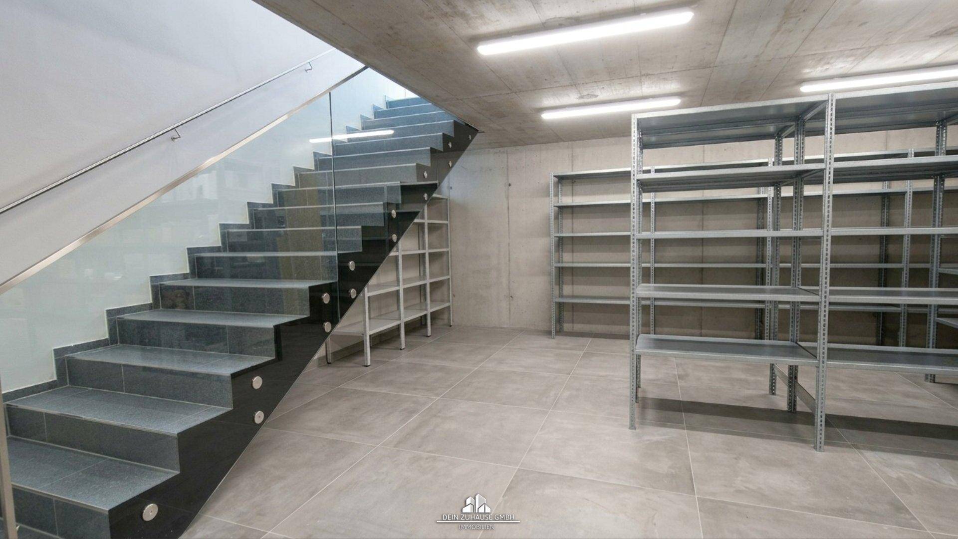 Geräumiger Lagerraum im Untergeschoss mit moderner Treppe und Metallregalen.