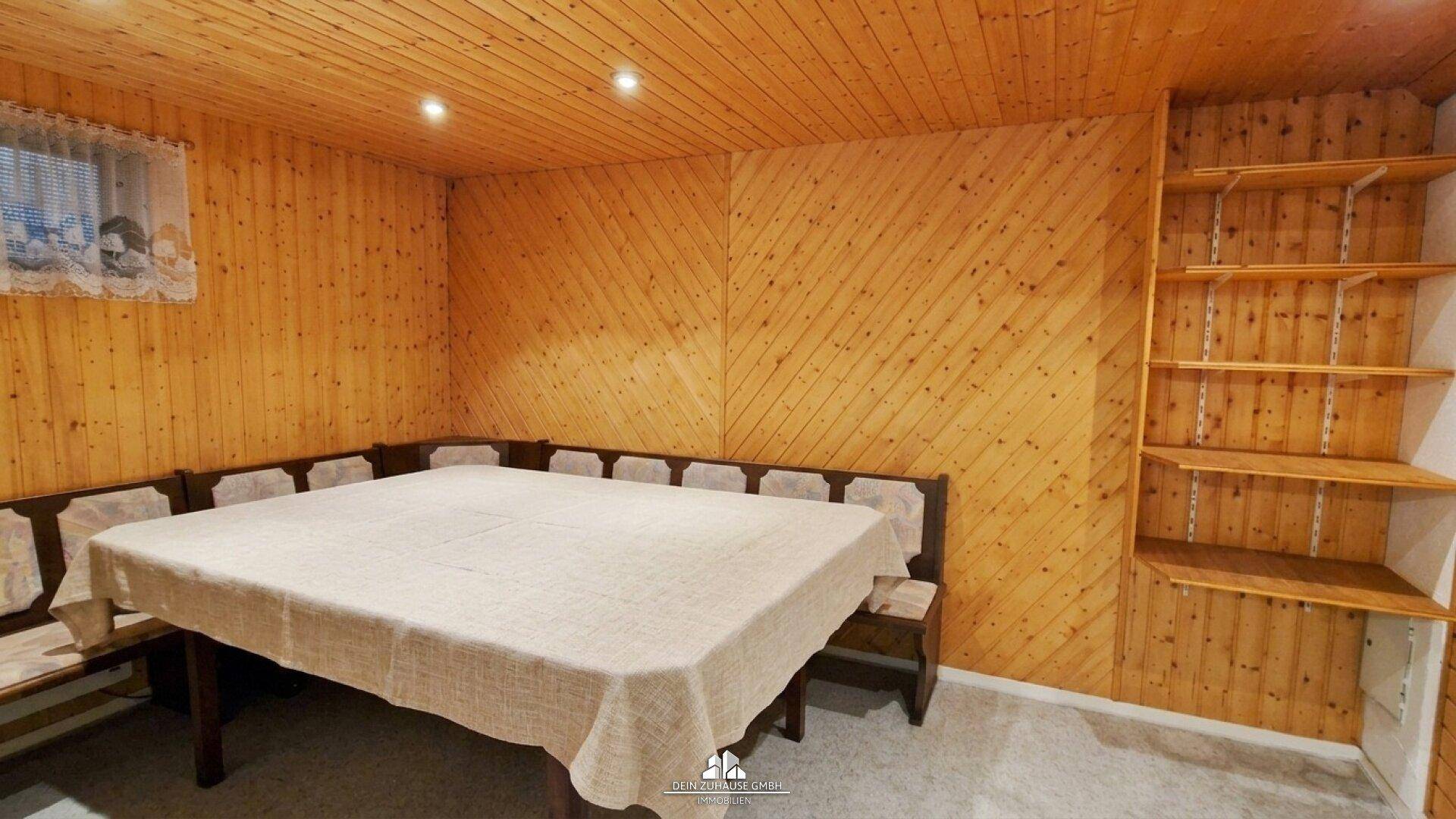 Gemütlicher Hobbyraum im Keller mit Holzvertäfelung und Sitzecke.