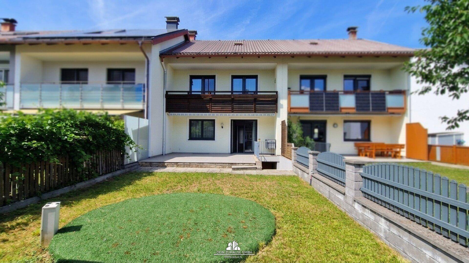 Hinteransicht der Reihenhäuser mit kleinem Gartenbereich und Balkonen.