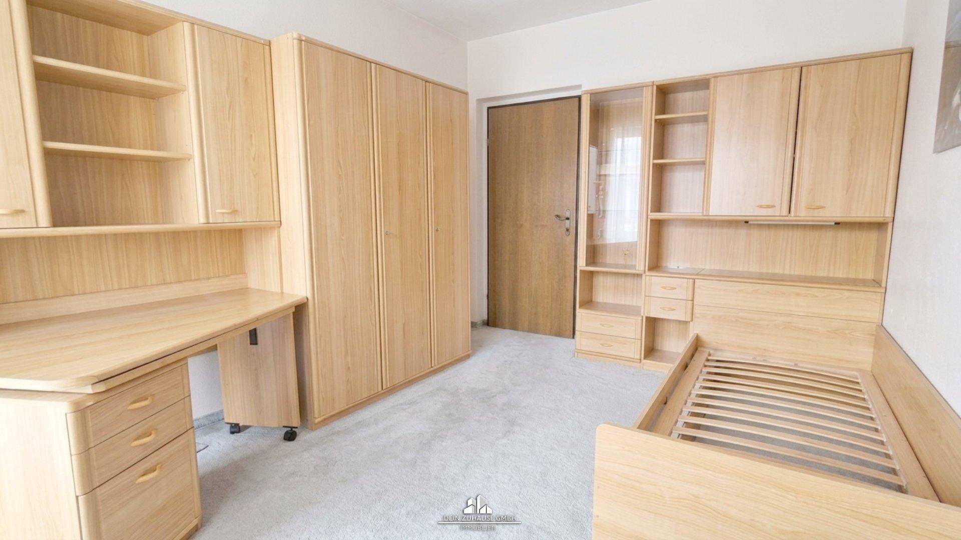 Schlafzimmer oder Arbeitszimmer mit Holzmöbeln, Bett und Regalsystem.