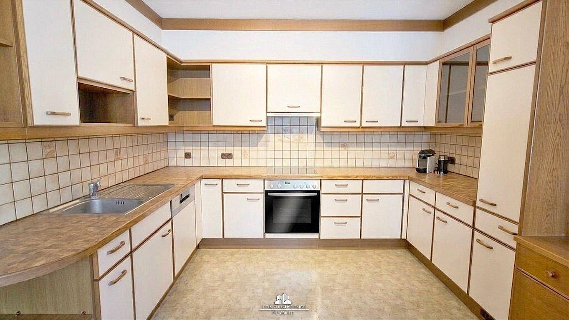 Funktionale Küche mit hellen Schränken, Fliesenrückwand und integriertem Backofen.