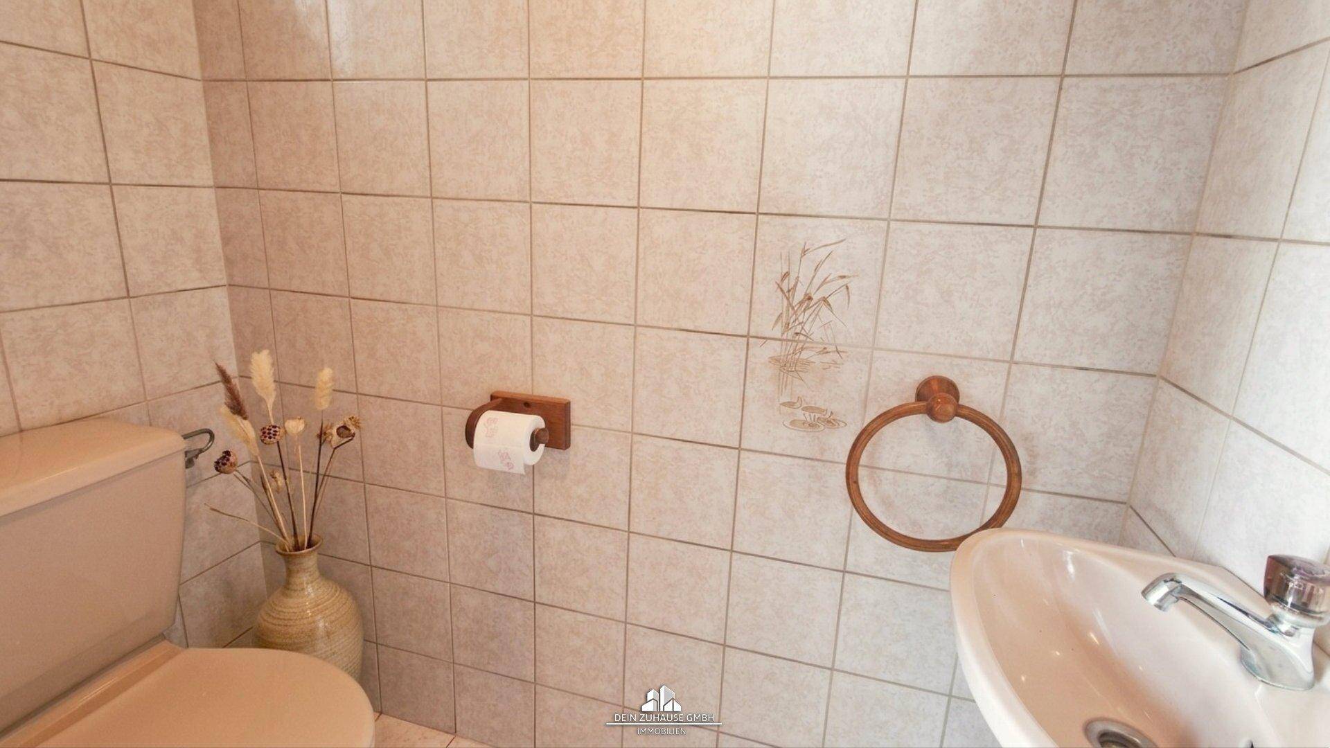 Kleines Gäste-WC mit hellen Fliesen und einfacher Ausstattung.
