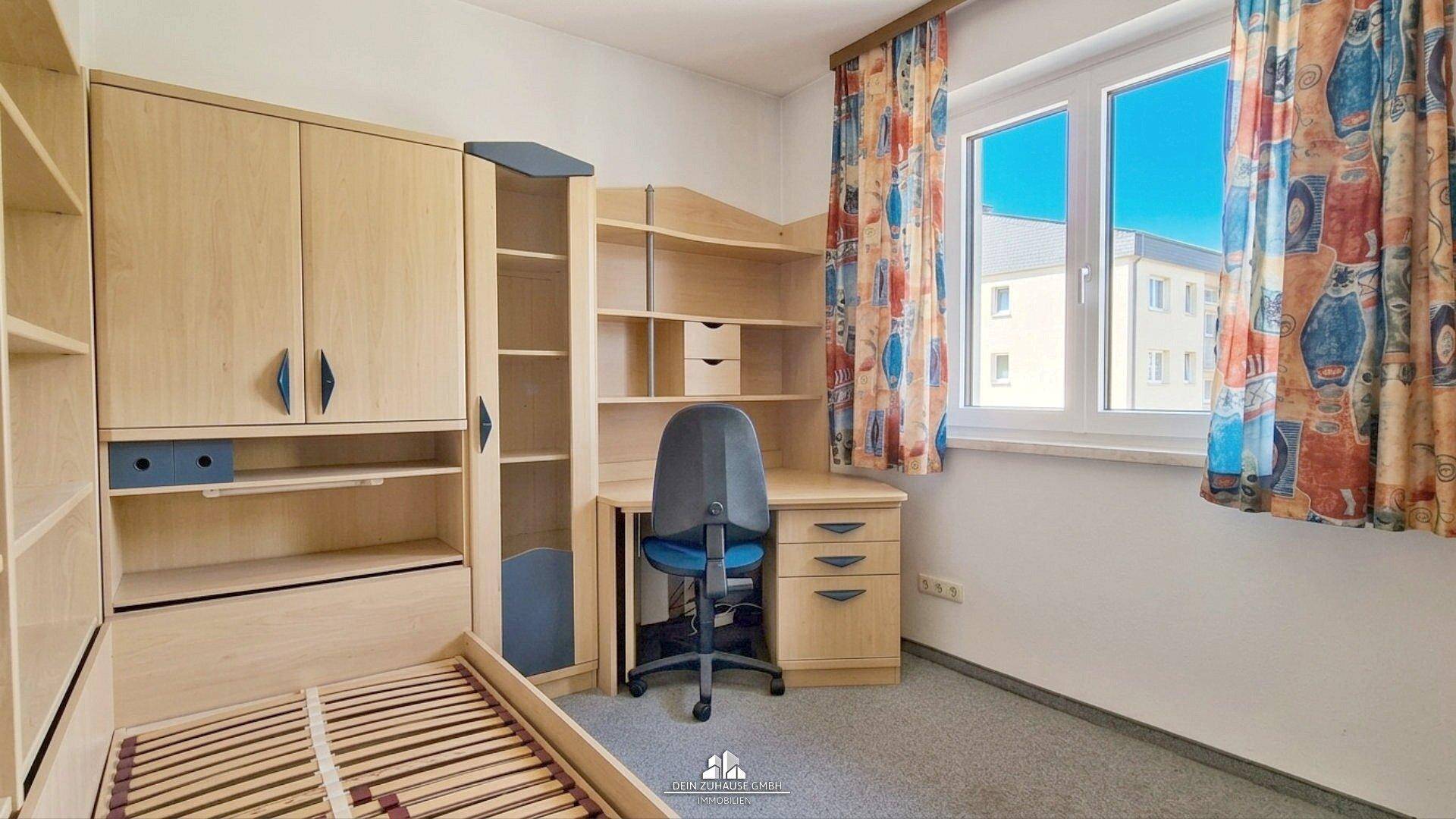 Kinderzimmer oder Arbeitszimmer mit Schreibtisch, Bett und blauen Akzenten.