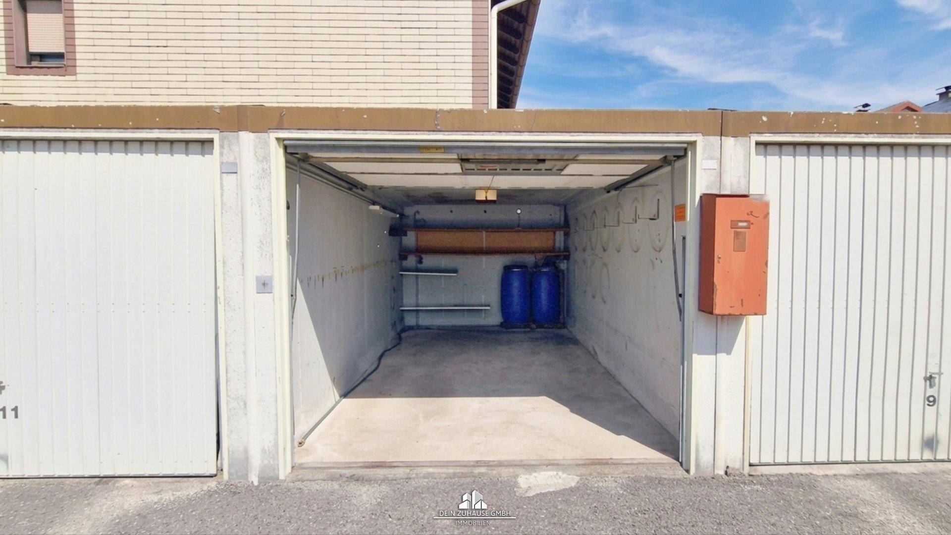 Einzelgarage mit offenem Tor und Betonboden.