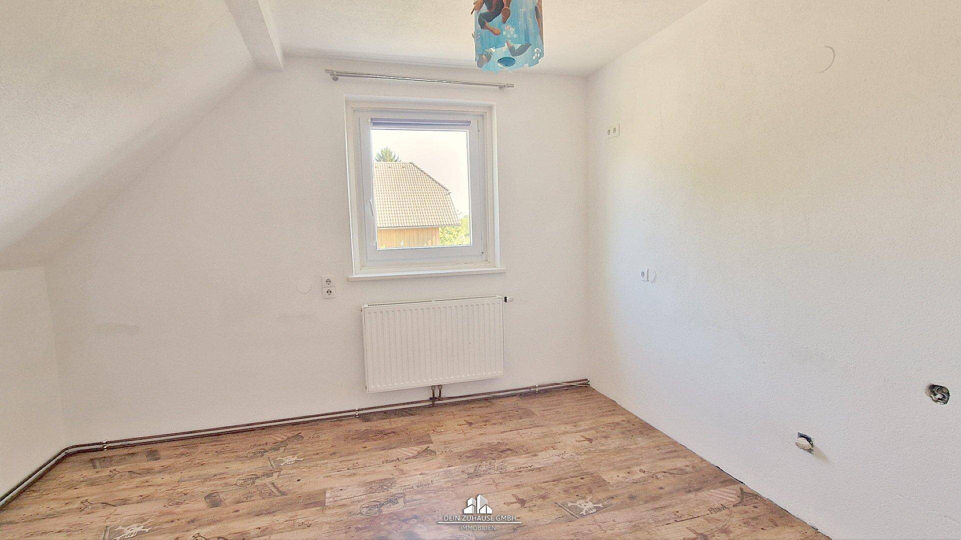 Helles Schlafzimmer im Dachgeschoss mit Laminatboden, Fenster und schrägen Wänden.