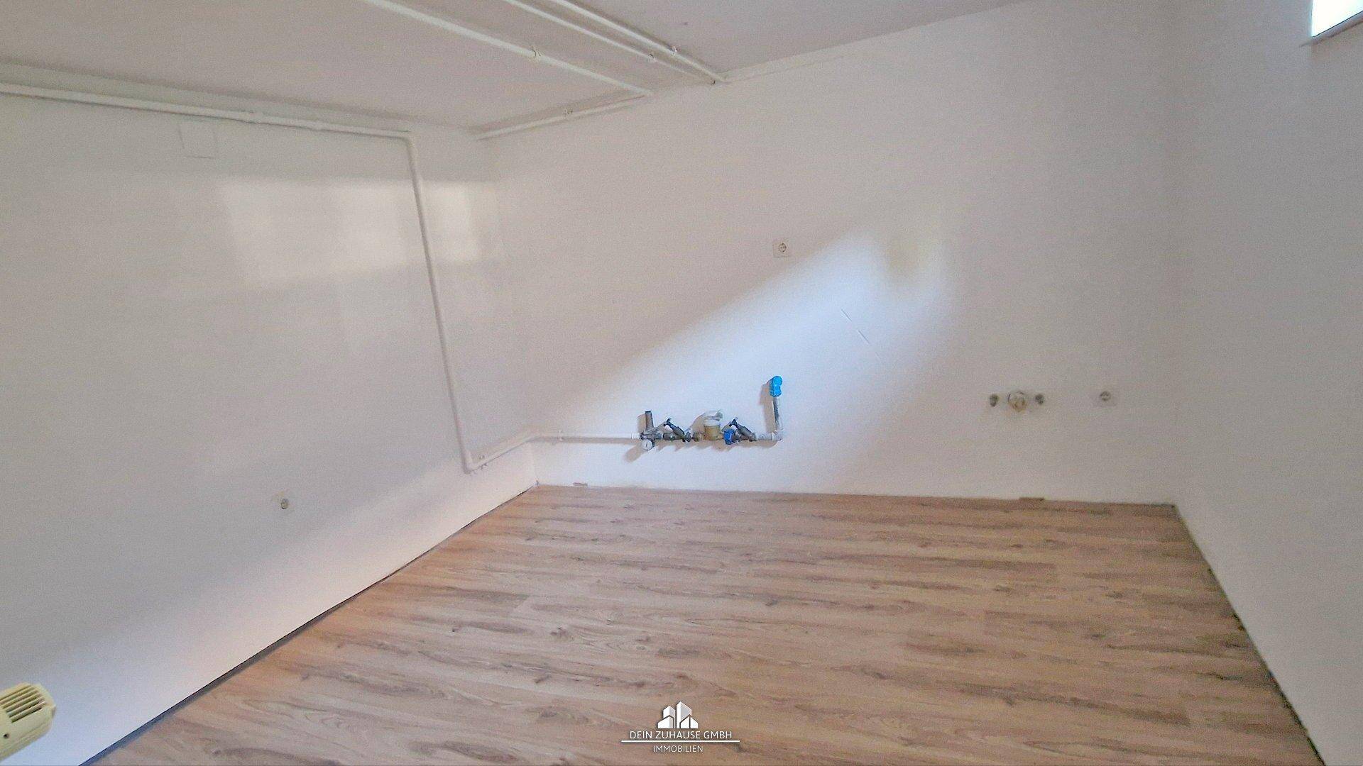 Heller Kellerraum mit Laminatboden und sichtbaren Leitungen, vielseitig nutzbar als Hobbyraum.