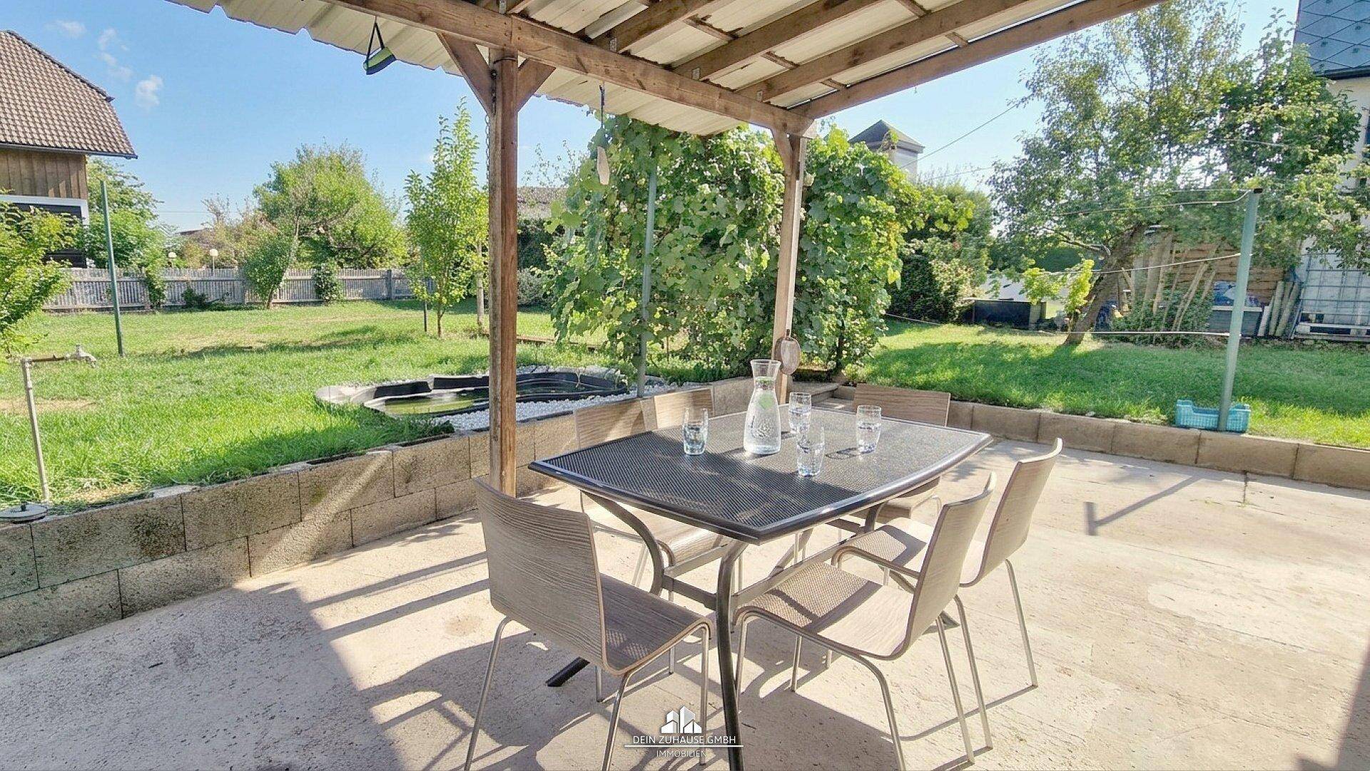 Überdachte Terrasse mit Esstisch und Stühlen, ideal für Mahlzeiten im Freien mit Gartenblick.