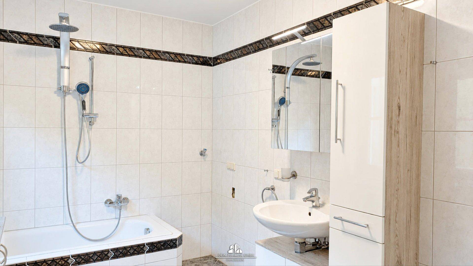 Badezimmer mit Badewanne, Waschbecken, Spiegelschrank und weißen Fliesen.