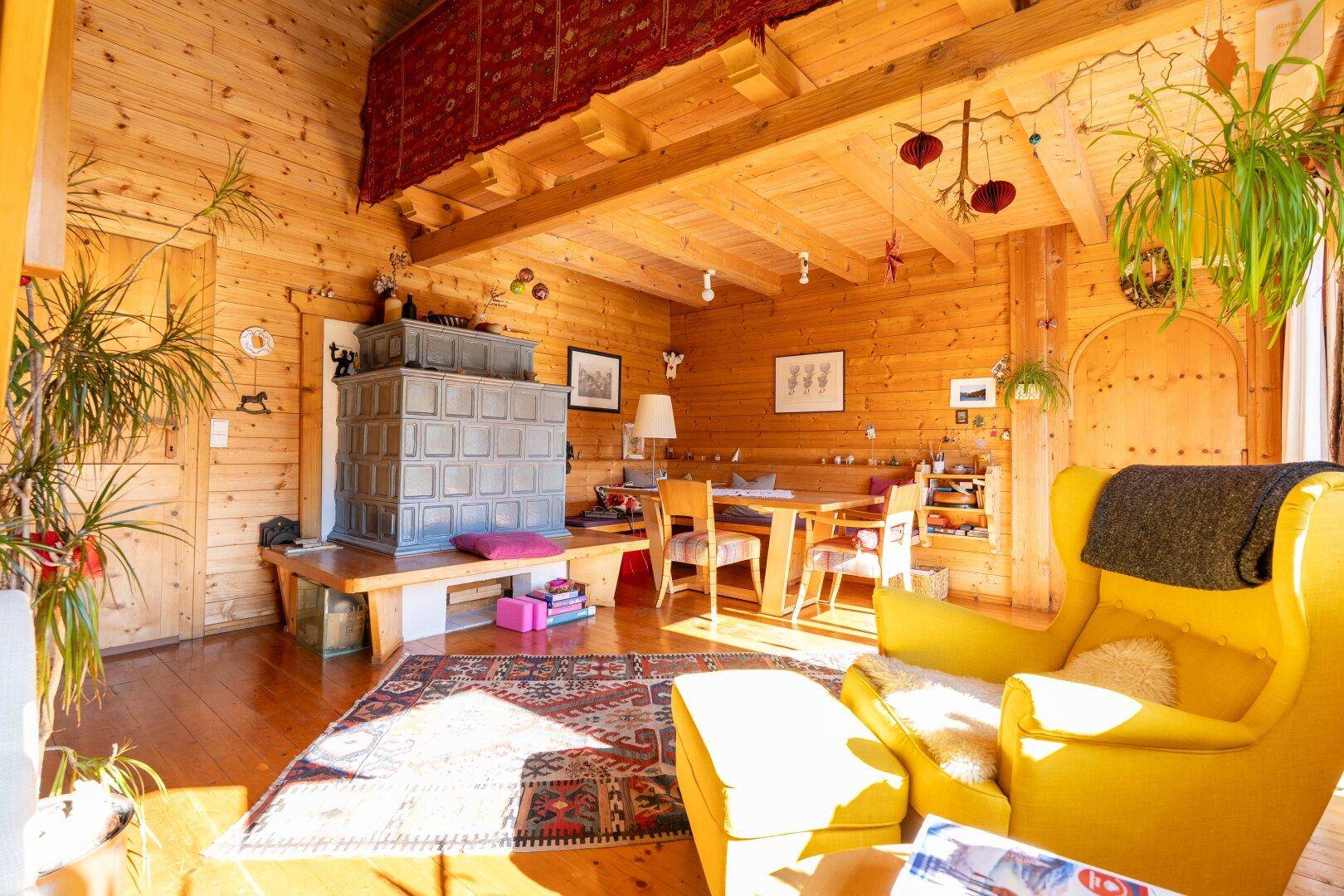 Rustikales Wohnzimmer im alpinen Stil mit Holzwänden, Kachelofen und gemütlicher Einrichtung.