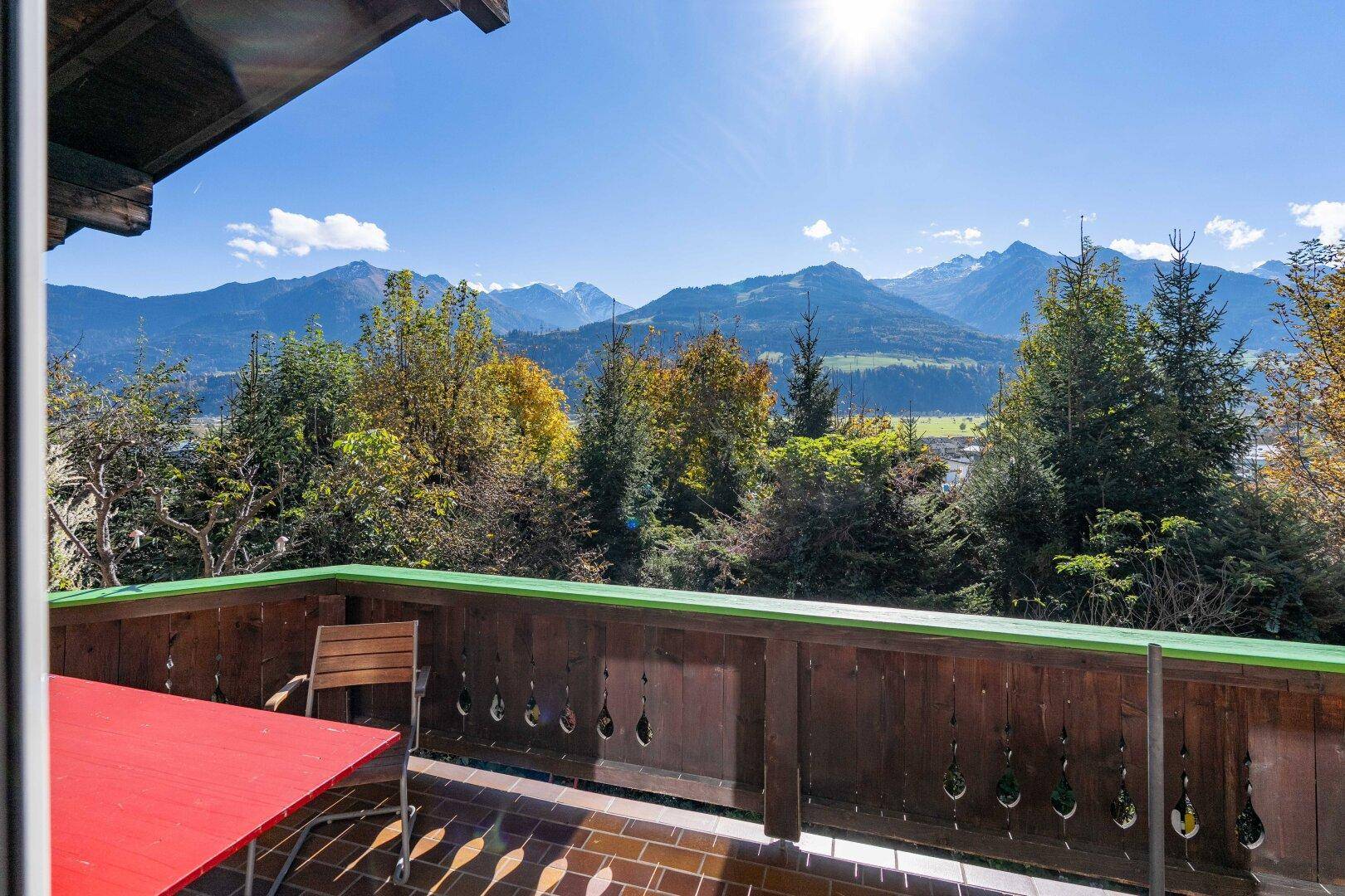 Sonniger Balkon mit Holzboden und atemberaubendem Panoramablick auf die Berge.