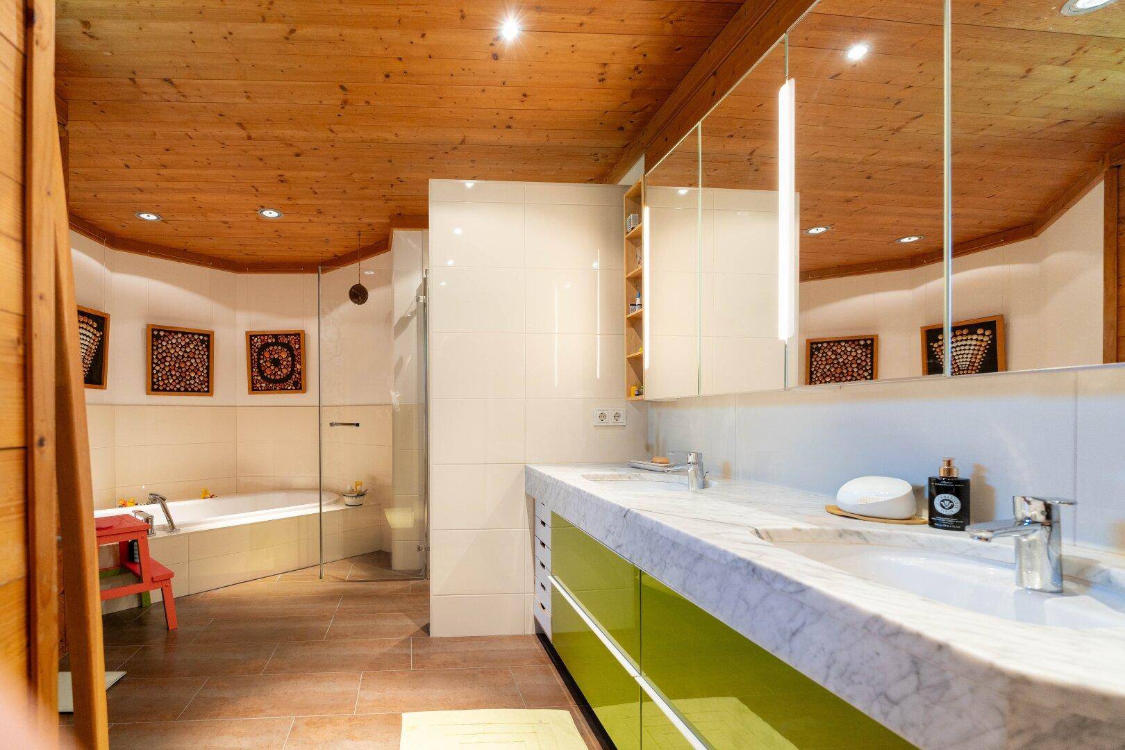 Modernes Badezimmer mit Doppelwaschbecken, großer Spiegelfront und Eckbadewanne.