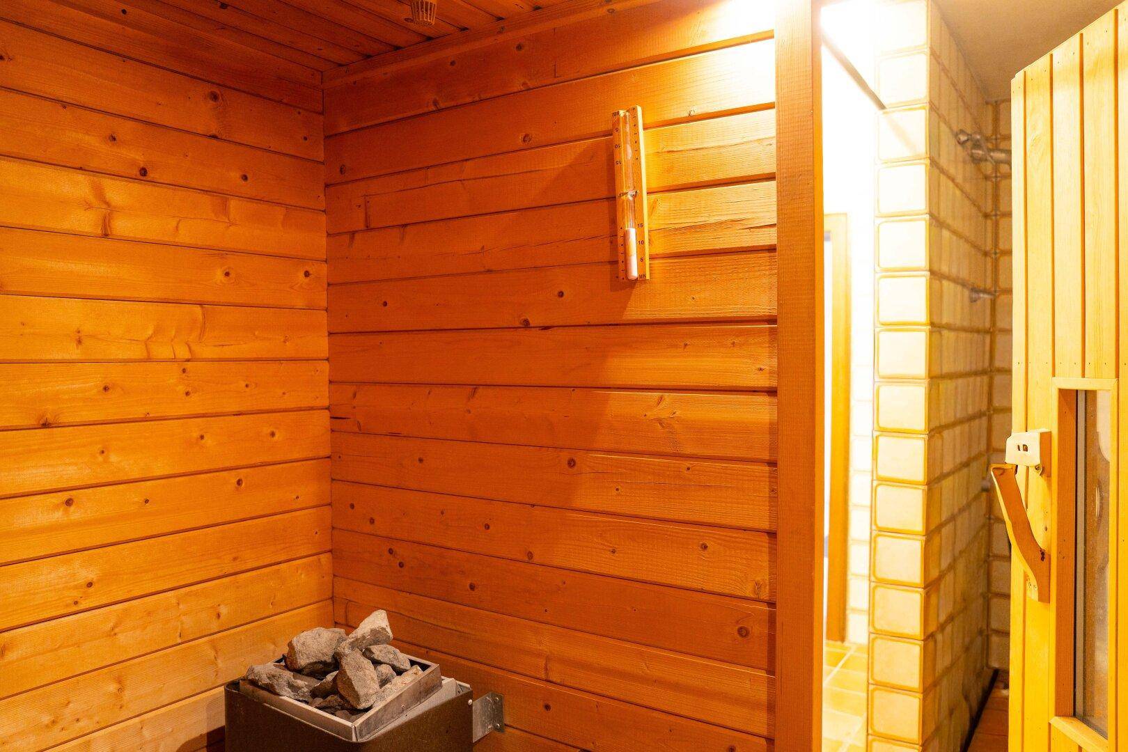 Gemütlicher Saunabereich mit Holzverkleidung, traditionellem Saunaofen und warmem Licht.