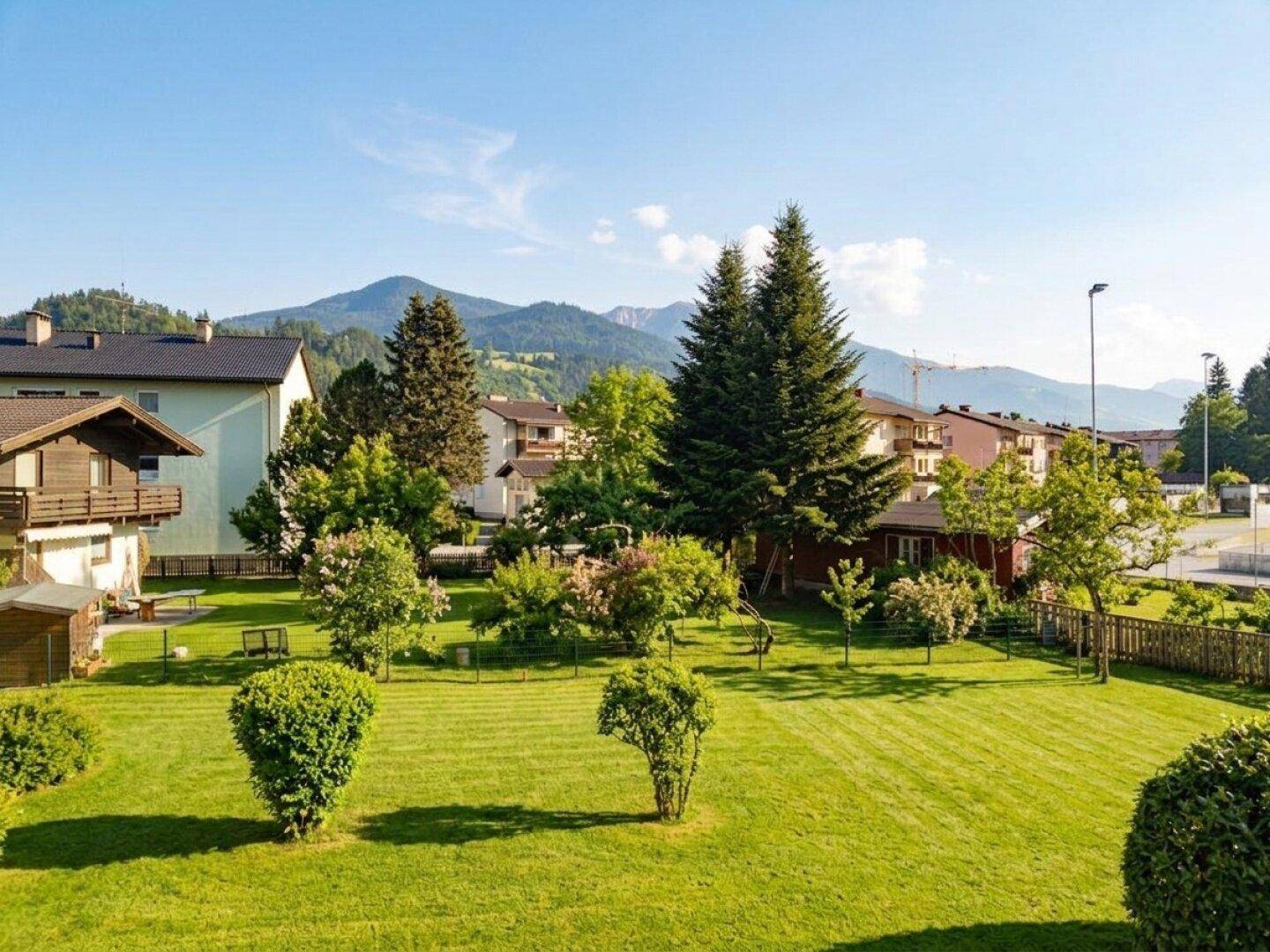 Gepflegter Garten mit weitläufiger Rasenfläche, Bäumen und malerischem Bergblick.