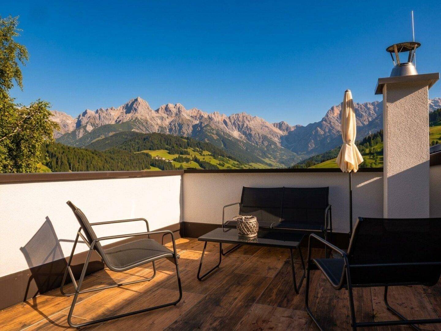 Sonnenterrasse mit modernen Gartenmöbeln und atemberaubendem Bergblick.