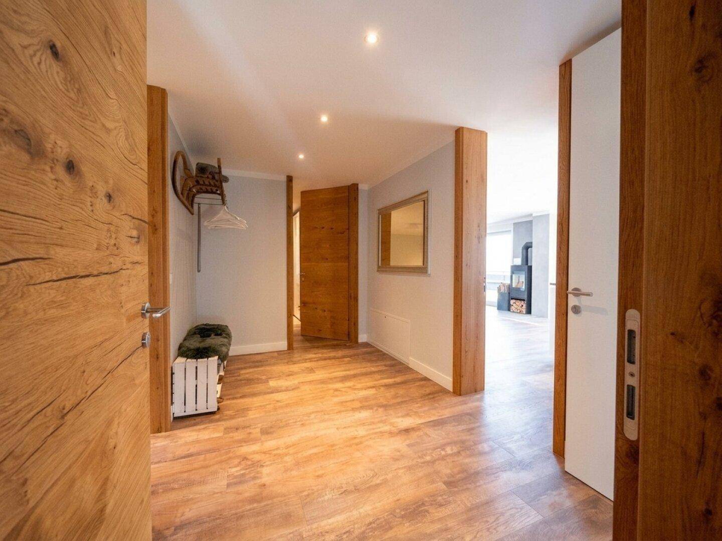 Heller Flur mit Holzboden und Holztüren, der zu verschiedenen Räumen führt.