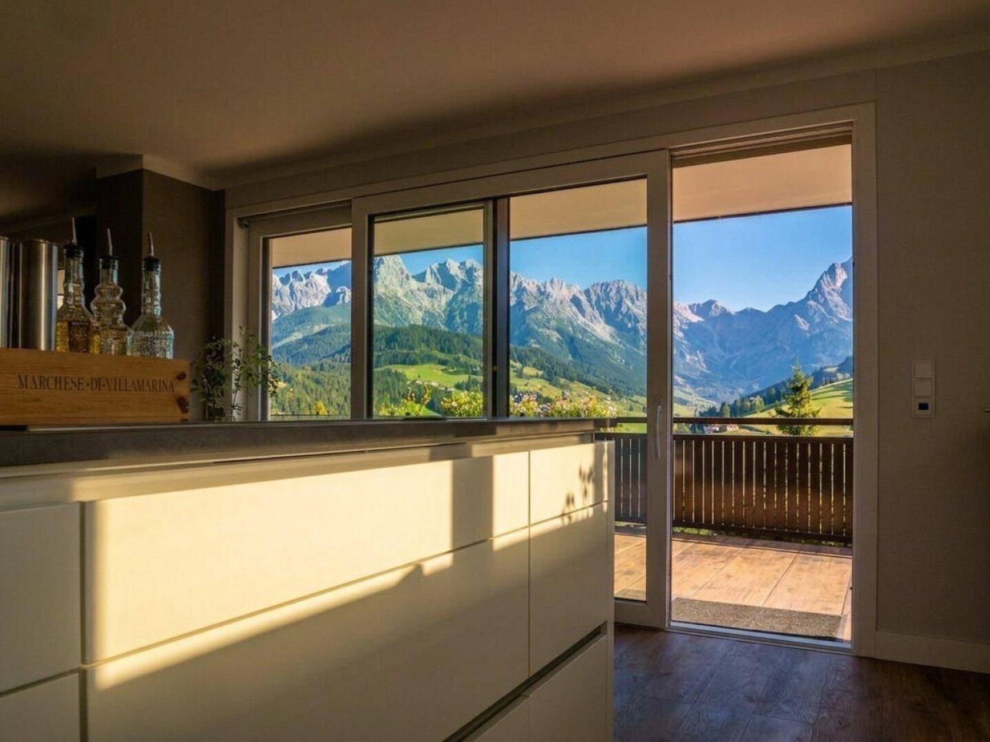 Moderne Küche mit Arbeitsplatte und Schiebetür zu einer Terrasse mit Bergblick.