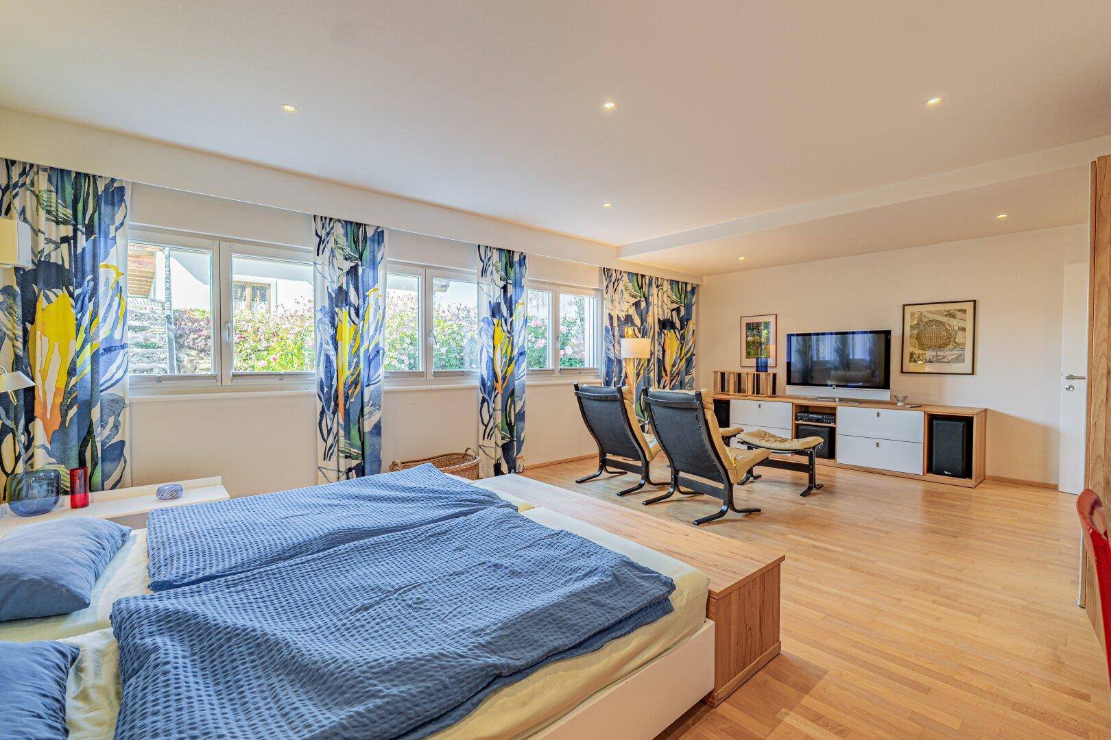Geräumiges Schlafzimmer mit zwei Betten, Holzboden und farbenfrohen Vorhängen.