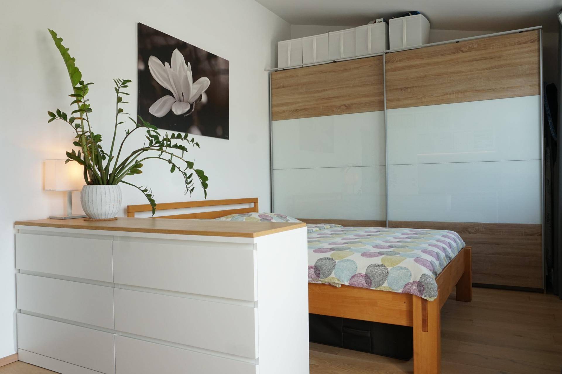 Schlafzimmer mit Doppelbett, Kommode und großem Schiebetürenschrank.