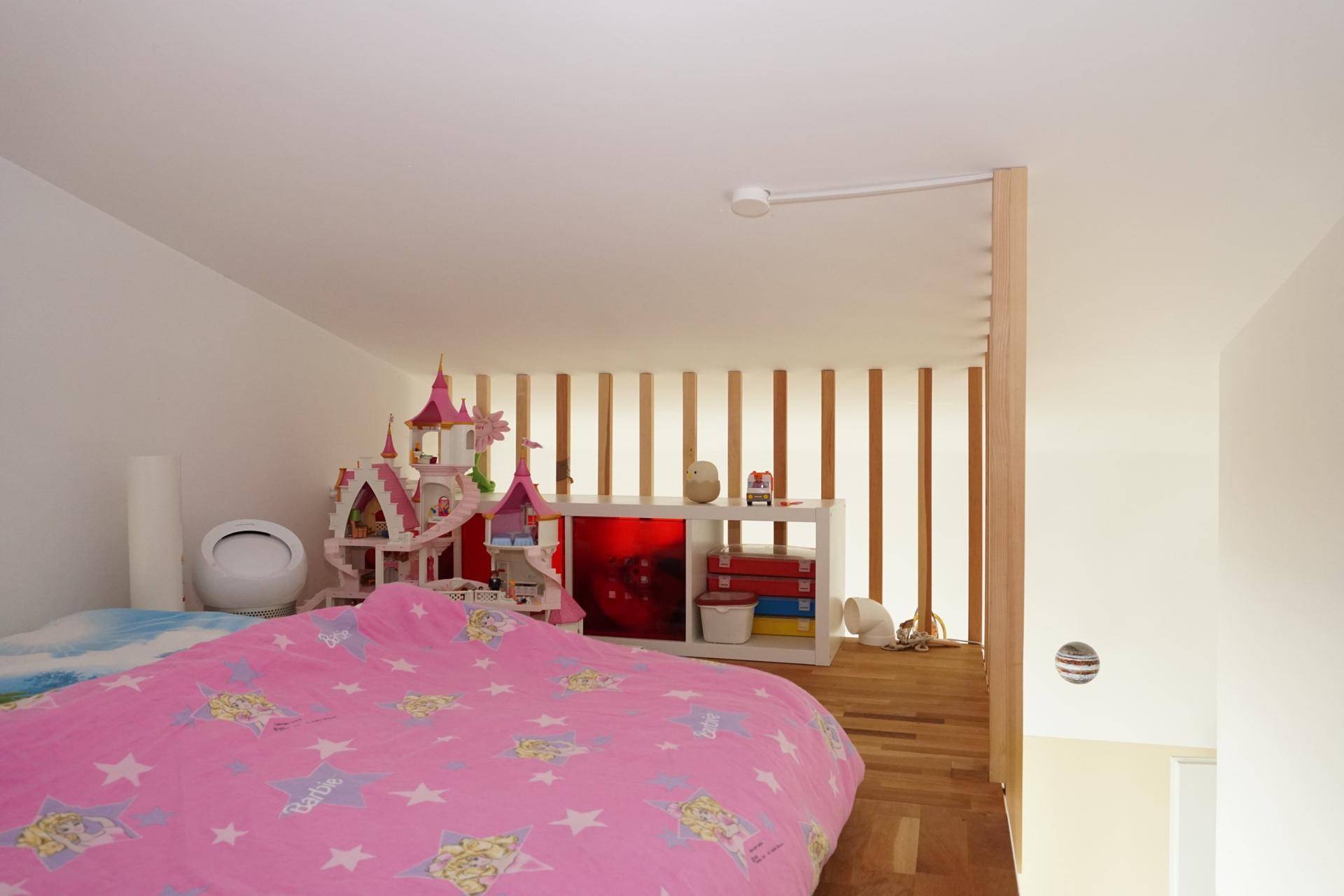 Kinderzimmer mit Bett, Spielzeug und Holzelementen, hell und freundlich gestaltet.