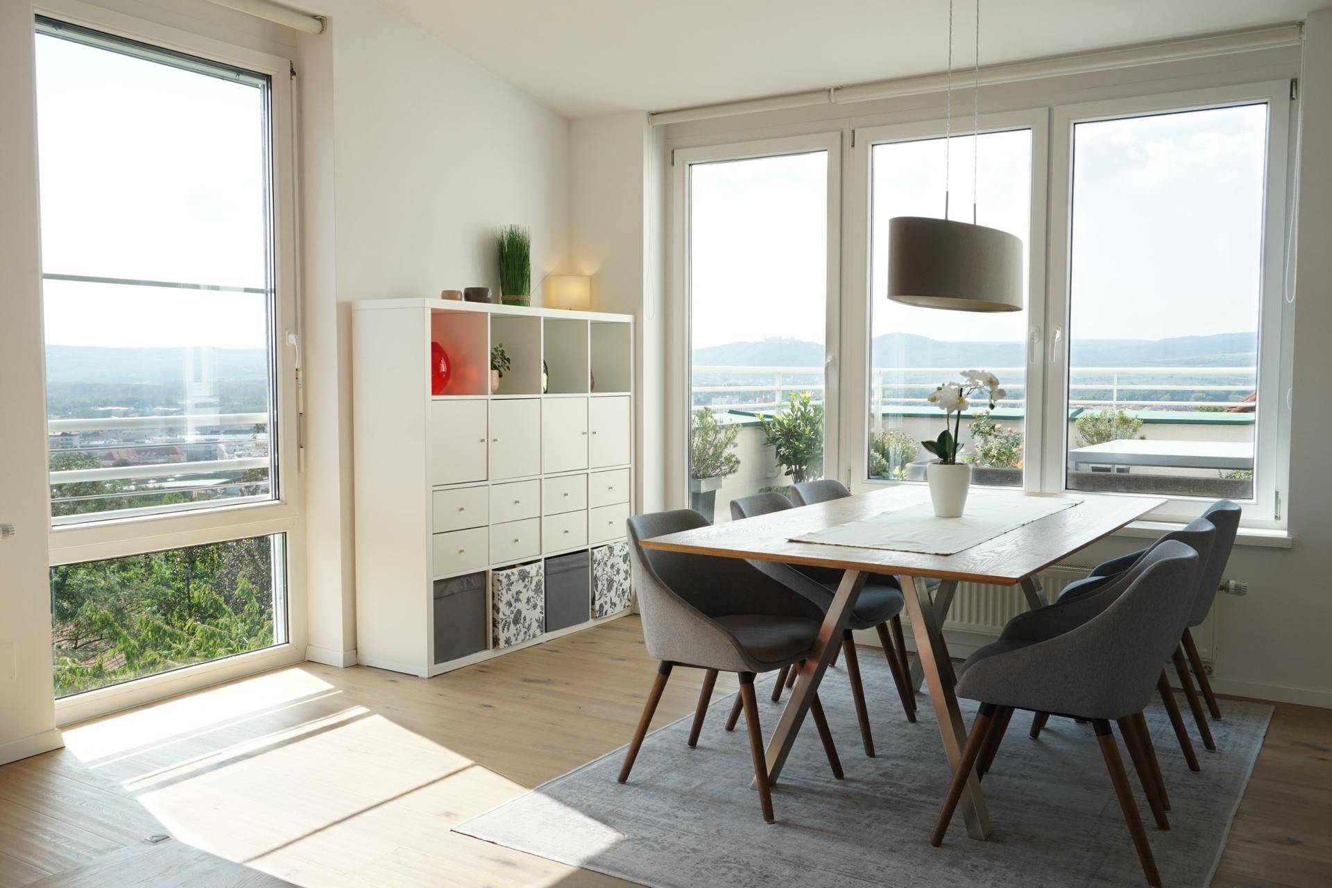Heller Essbereich mit Holztisch, modernen Stühlen und großen Fenstern mit Panoramablick.