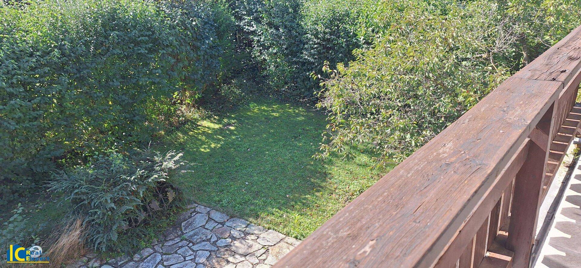 Blick von oben auf einen naturbelassenen Gartenbereich mit Steinplattenweg und üppigem Grün.